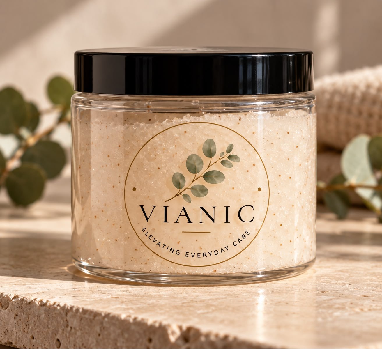 A jar of Vianic sugar scrub on travertine with eucalyptus